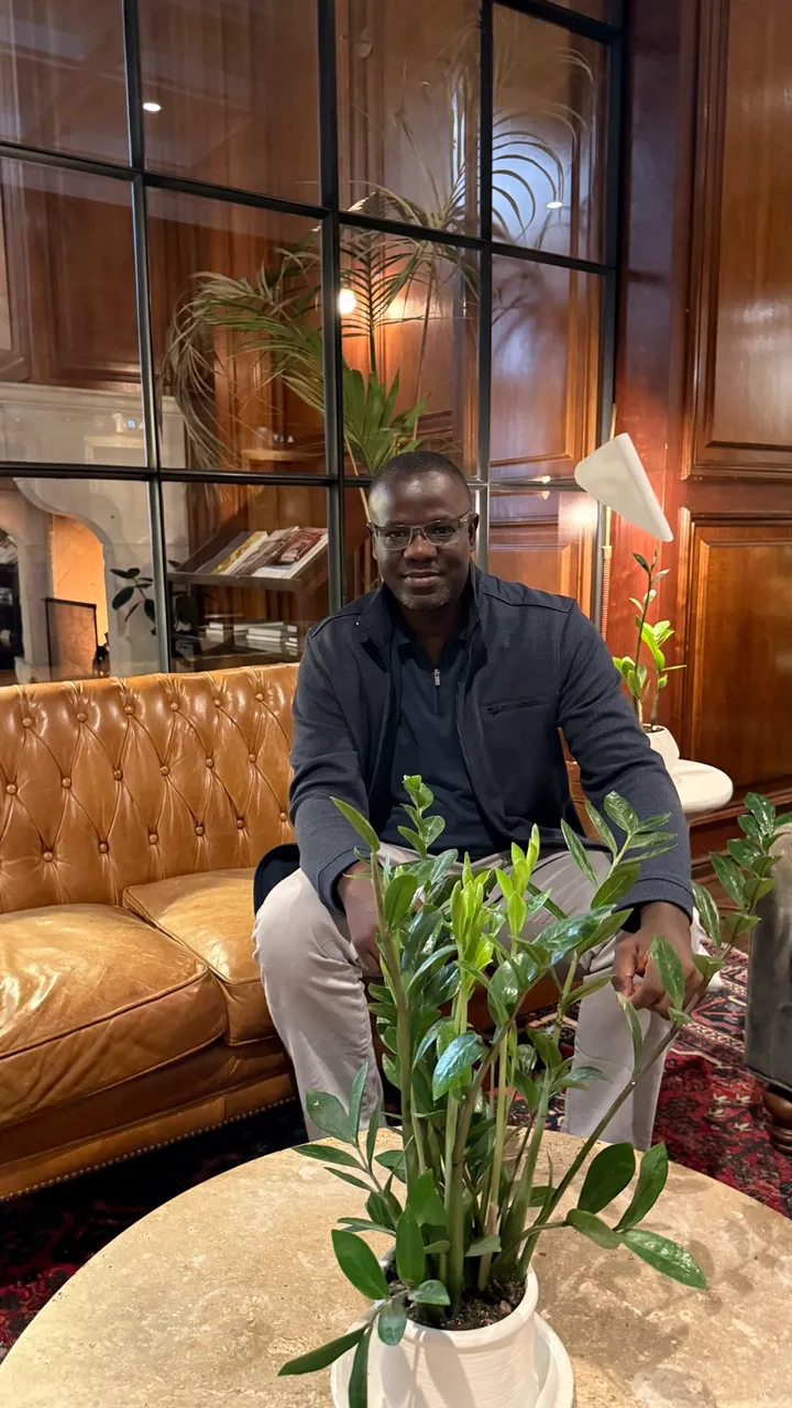 Tamba Sheku Lamin seated indoors, smiling, in a dark jacket